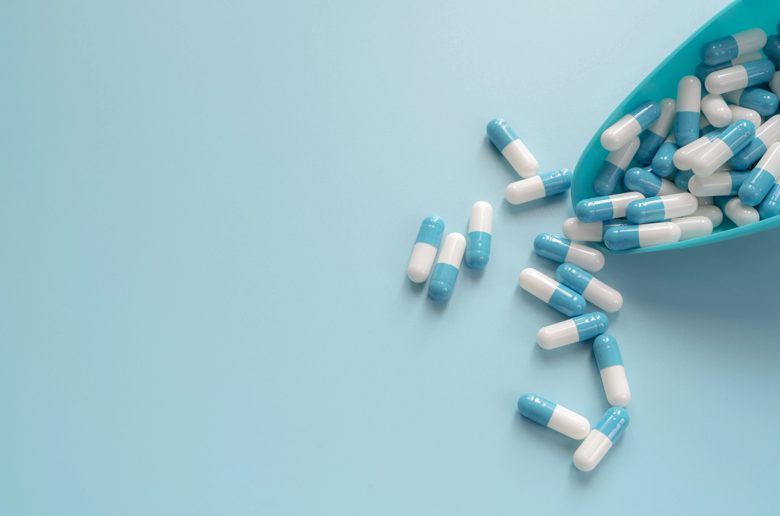 Adderall Effects on Personality: Blue and white pill capsules on a pale blue background.