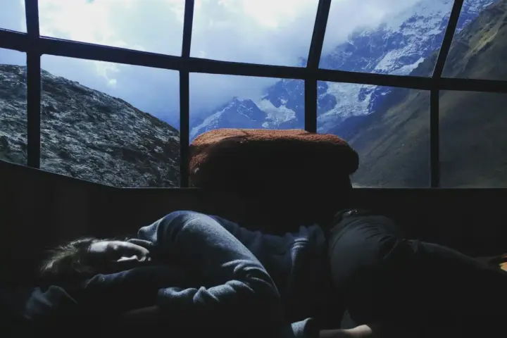 Person sleeping at a desk by a picturesque window looking out at a mountain scene