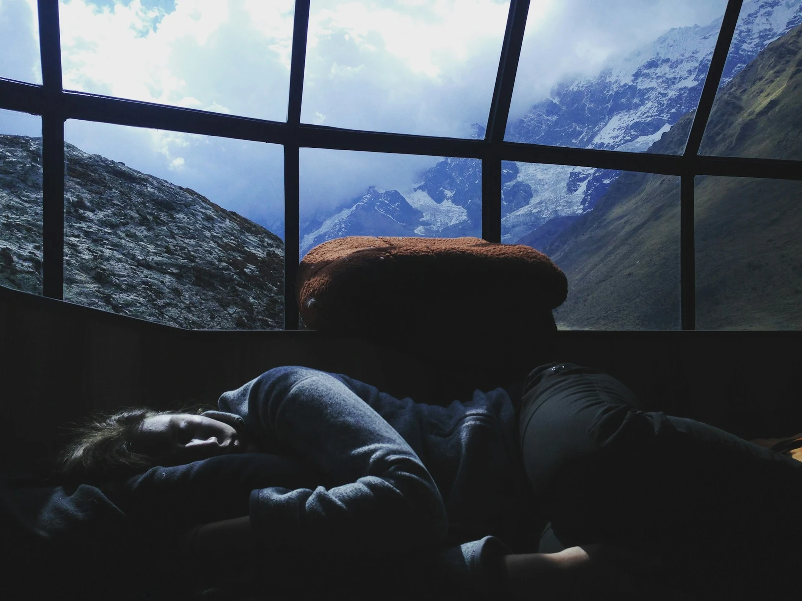 Person sleeping at a desk by a picturesque window looking out at a mountain scene