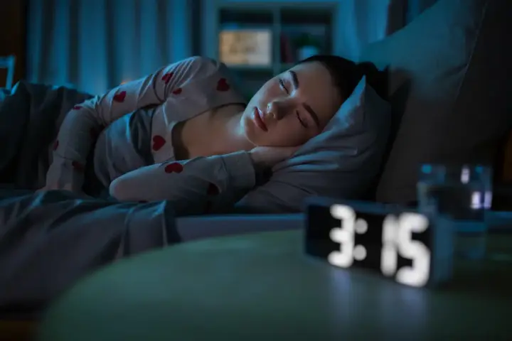 Eszopiclone Long-Term vs. Short-Term Use: A woman laying in bed struggling with insomnia. The clock says 3:15