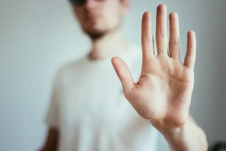 The HALT Acronym: A person standing out of focus with their hand forward as if saying HALT