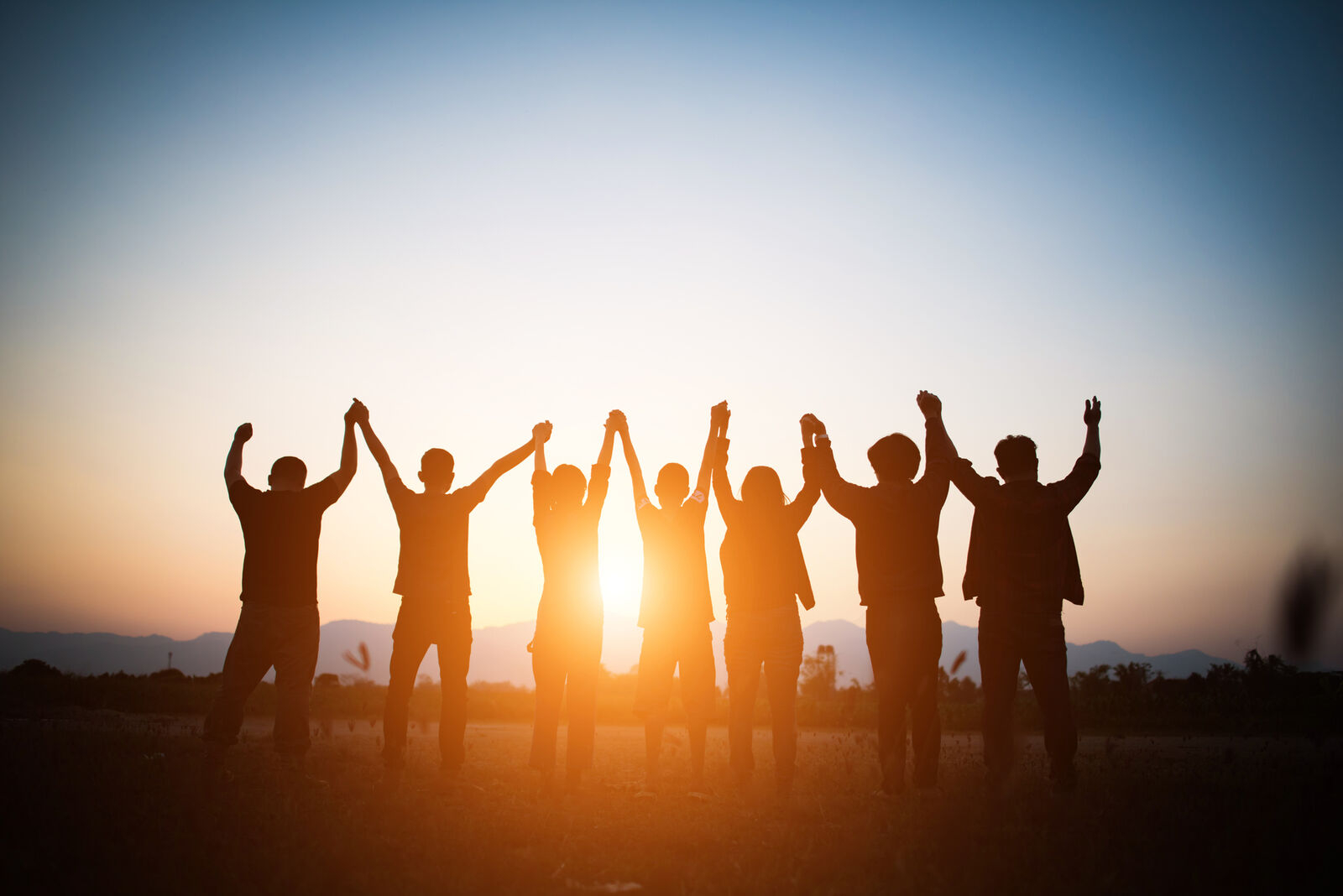 The AA Prayer: A group of people with their hands held in the air during sunset.